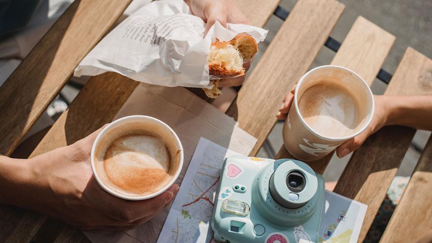 Essen und Getränke "to go" produzieren viel Verpackungsmüll: Auf einem Tisch stehen Kaffeebecher und ein eingepacktes Brötchen